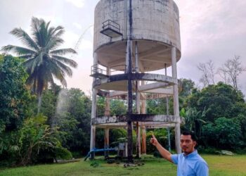 MOHD. Shahrir Abdul Rahman menunjukkan air yang melimpah keluar dari tangki utama Rumah Awam Kos Rendah Binjai Kemaman, Terengganu. – UTUSAN/NIK NUR IZZATUL HAZWANI NIK ADNAN