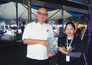 SHIMA Sidek (kanan) menyampaikan buku karyanya kepada seorang pembeli, Ahmad Nizam Hamid di Temerloh, Pahang. – UTUSAN/SALEHUDIN MAT RASAD
