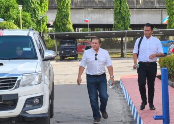 HAMID Ismail (kiri) mengiringi kereta yang dinaiki Noraidah Lamat selepas penyerahan telefon bimbit di Balai Polis Karamunsing, Sabah.