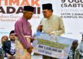 ANWAR Ibrahim (kanan) menyampaikan sumbangan kepada pondok-pondok yang menghadiri Majlis Ijtima MADANI Ulama dan Guru Pondok Kelantan di UiTM Machang, Kelantan hari ini.-UTUSAN/KAMARUL BISMI KAMARUZAMAN 