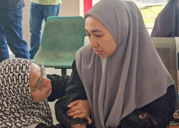 NORLIANA Mohd. Ali (kanan) ditenangkan rakan ketika menunggu urusan bedah siasat suaminya di Jabatan Perubatan Forensik Hospital Melaka, semalam. – UTUSAN/AMRAN ALI