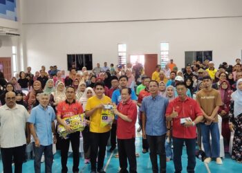 AHMAD Maslan (tengah) menyampaikan sumbangan kepada pelajar melanjutkan pelajaran di Dewan Kompleks Muafakat Sungai Pinggan, Benut, Pontian, Johor.