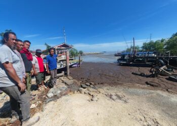 ABU Hasan Othman (kanan) menunjukkan keadaan air laut yang kering di Jeti Pangkalan Nelayan Pantai Siring, Jasin, Melaka hingga menyukarkan bot keluar dan masuk. – UTUSAN/AMRAN ALI