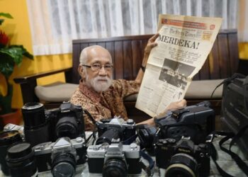 ABDUL Khalil Abdul Rahim menunjukkan akhbar  The Straits Times yang melaporkan mengenai kemerdekaan Tanah Melayu dan koleksi kamera antik miliknya. – UTUSAN/NUR SHARIEZA ISMAIL.