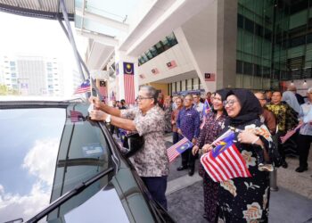 AARON Ago Dagang melekatkan Jalur Gemilang pada sebuah kereta ketika Majlis Pelancaran Bulan Kebangsaan, Kementerian Perpaduan Negara di Putrajaya baru-baru ini.-UTUSAN