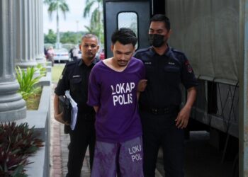 TERTUDUH dibawa polis untuk menghadiri prosiding perbicaraan di Mahkamah Sesyen Pasir Mas, Kelantan. - UTUSAN/KAMARUL BISMI KAMARUZAMAN