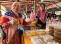 HAFIDZAH Mustakim (kiri) memasang Jalur Gemilang di Pasar Kubang Pasu Kota Bharu, Kelantan. - UTUSAN/ ROSLIZA MOHAMED