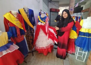 ZAMZURINA Abdul Kadir menunjukkan antara koleksi pakaian bertema kemerdekaan yang ditawarkan di kedainya di Bandar Jerteh, Besut, Terengganu. - UTUSAN / WAN ZURATIKAH IFFAH WAN ZULKIFLI