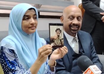 UMMU Haiman Bee Daulatgun (kiri) menunjukkan gambar anaknya dalam sidang akhbar bersama Naran Singh di Ipoh, baru-baru ini. - UTUSAN
