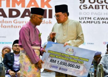 ANWAR Ibrahim (kanan) menyampaikan sumbangan kepada pondok-pondok yang menghadiri Majlis Ijtima Madani Ulama dan Guru Pondok Kelantan di UiTM Machang, Kelantan hari ini. - UTUSAN/KAMARUL BISMI KAMARUZAMAN 