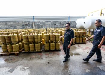 KAMALLUDIN Ismail (kiri) menunjukkan  gas petroleum cecair (LPG) bersubsidi yang ditemukan dalam stor di Kawasan Perindustrian Bemban di Batu Gajah ketika serbuan semalam - UTUSAN/MUHAMAD NAZREEN SYAH MUSTHAFA