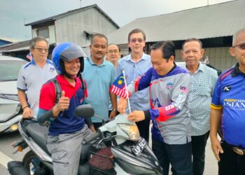 AHMAD Maslan memasang Jalur Gemilang di kenderaan di Pekan Kayu Ara Pasong, Pontian, Johor.