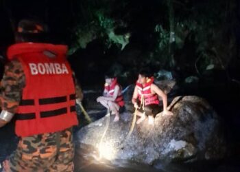 ANGGOTA bomba menyelamatkan pelajar yang terperangkap di tengah sungai dalam kejadian kepala air di Tanjung Malim hari ini. - UTUSAN
