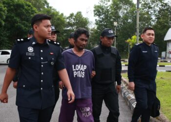 TERTUDUH diiringi anggota polis semasa menghadiri prosiding perbicaraan di Mahkmah Majistret Kuala Krai, Kelantan. - UTUSAN/KAMARUL BISMI KAMARUZAMAN