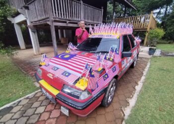 WAN Mustafa Wan Hasan menunjukkan kereta Proton Saga Iswara Aeroback miliknya yang dipasang bendera Malaysia ketika ditemui di Jerteh, Besut, Terengganu. - UTUSAN/WAN ZURATIKAH IFFAH WAN ZULKIFLI