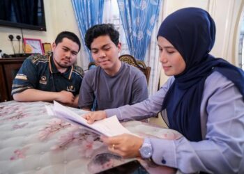 MUHD. IMRAN Zakaria (tengah) bersama abangnya, Muhd. Akram (kiri) menerima faedah Pencen Penakat yang disampaikan oleh wakil Perkeso di kediaman mereka di Kampung Melayu, Batu Caves, Selayang, hari ini.