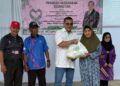 NIZAM Abu Bakar Titingan menyampaikan sumbangan kepada salah seorang penduduk di Kampung Batu Payung, Tawau, hari ini. - UTUSAN/BESSE AISYAH