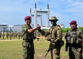 TENGKU Muhammad Fauzi Tengku Ibrahim (kiri) menyampaikan Anugerah Penuntut Keseluruhan Terbaik kepada Muhammad Haikal Abdullah pada Majlis Penutup Kursus Asas Pasukan Atur Cepat (APAC) di Dataran Drawbridge, Kuala Terengganu, Terengganu. - UTUSAN/PUQTRA HAIRRY