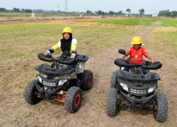 PENGUNJUNG menunggang ATV di sekitar kawasan sawah di Sungai Manik, Pasir Salak. – UTUSAN/ZULFACHRI ZULKIFLI