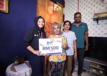 Wakil Media Mulia Sdn. Bhd. Ayda Kamaruddin (kiri) menyerahkan bantuan Hati Mulia kepada penerima bantuan Perkeso, M. Susilah (dua kiri) di Taman Rhu Permai, Kuala Selangor. - UTUSAN/AFIQ RAZALI