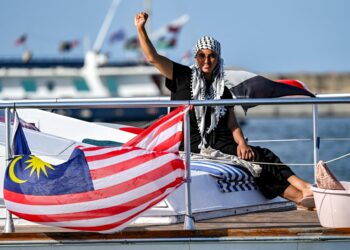 Seorang wanita memberi isyarat ketika dia menaiki kapal bersama aktivis dan pembela hak asasi manusia lain, berlepas dari pelabuhan Bizerte di utara Tunisia, pada 14 September 2025 untuk menyertai bot terakhir yang mengambil bahagian dalam Flotilla Sumud Global, menuju ke Gaza untuk memecahkan sekatan Israel 
di wilayah Palestin. – AFP
