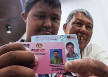 TEOH Zheng Yan (kiri) menunjukkan kad pengenalan dan kad orang kurang upaya (OKU) ketika ditemui di Pusat Transit Gelandangan Pulau Pinang di George Town, Pulau Pinang semalam. – UTUSAN/DANIAL SAAD