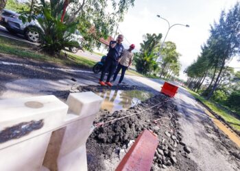 SHADAN Othman (kanan) meninjau keadaan Jalan Alai Perdana, Melaka yang rosak sejak lebih tiga minggu lalu.