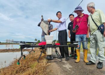 LIM Ban Hong (empat dari kanan) menyaksikan demonstrasi penggunaan dron bagi penaburan benih padi di kawasan sawah padi di Bukit Rambai, Melaka hari ini. - UTUSAN/AMRAN ALI