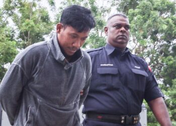MUHAMMAD Amirulhakim Shuhaimi (kiri) diiringi oleh seorang anggota polis ketika tiba di Mahkamah Majistret Balik Pulau, Pulau Pinang hari ini.-UTUSAN/DANIAL SAAD