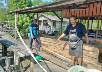 ZAINI Ali (kanan) menunjukkan keadaan  jeti yang rosak di Pengkalan Nelayan Parit Penghulu, Serkat di Pontian, Johor.
