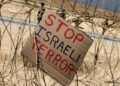 PLAKAD tertulis 'hentikan keganasan Israel' diletakkan di pagar sempadan Israel-Gaza. - AFP