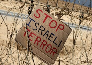 PLAKAD tertulis 'hentikan keganasan Israel' diletakkan di pagar sempadan Israel-Gaza. - AFP