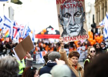 SEORANG penunjuk perasaan memegang sepanduk menggambarkan Perdana Menteri Israel, Benjamin Netanyahu semasa perarakan pro-Palestin di tengah London.- AFP