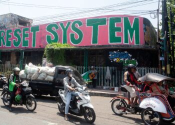 GRAFITI tertulis ‘Reset System yang dihasilkan oleh artis tempatan semasa protes kelihatan di sebalik lalu lintas di Yogyakarta, Indonesia.-AFP