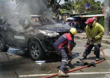 ANGGOTA bomba memadam sebuah kenderaan kerajaan yang dibakar penunjuk perasaan ketika bantahan pembelian 65 SUV oleh Parlimen di Dili, Timor Leste.-AFP