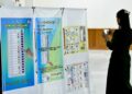 SEORANG wanita merakam gambar poster panduan pengundian semasa sidang media pertama UEC Myanmar di Naypyidaw.-AFP