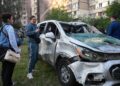 PENDUDUK berdiri berhampiran sebuah kereta yang rosak ketika anggota bomba memadamkan kebakaran di bangunan kediaman akibat bedilan dron dan peluru berpandu terbesar Russia di Kyiv. – AFP