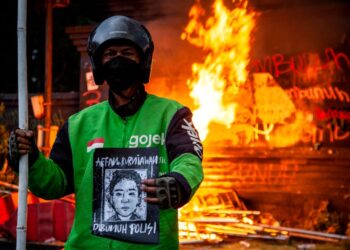 SEORANG penunggang motosikal e-hailing memegang potret Affan Kurniawan yang maut dilanggar kenderaan polis, ketika tunjuk perasaan di hadapan ibu pejabat Polis Metropolitan Jakarta Raya, 29 Ogos lalu.- AFP