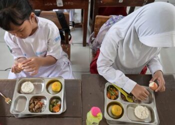MURID di sebuah sekolah rendah di Jakarta sedang menikmati hidangan yang disediakan menerusi program makanan percuma kerajaan.- AFP