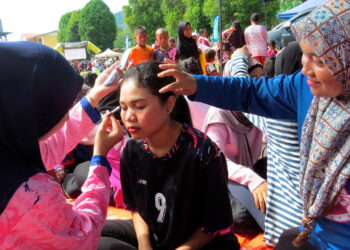 NUR Ain Natassya Mohd. Napi (kanan) melihat wakil Puteri UMNO menunjukkan asas solekan kepada gadis Orang Asli di Pos Balar, Gua Musang, Kelantan. – UTUSAN/ AIMUNI TUAN LAH