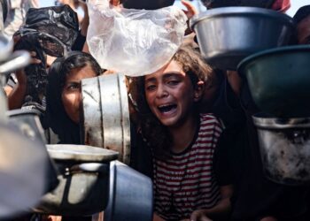 SEORANG kanak-kanak menangis ketika penduduk Palestin berebut untuk mendapatkan makanan di dapur komuniti di Khan Younis, selatan Gaza, kelmarin.- AFP