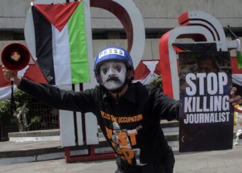 SEORANG penunjuk perasaan mmebawa plakad bertulis ‘Henti bunuh wartawan Gaza’ dalam demonstrasi membantah kekejaman Israel di Bandung, Indonesia. – AFP