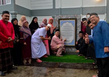 MOHD. Zubir Embong (duduk, tengah) menandatangani plak pada majlis penyerahan surau sekolah sempena sambutan Hari Kebangsaan ke-68 di Sekolah Menengah Sains Sultan Mahmud (Sesma) di Kuala Terengganu, Terengganu., semalam.- UTUSAN/PUQTRA HAIRRY