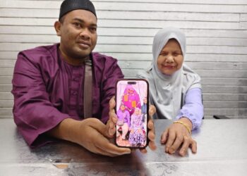 MOHD. Hafizey Mat Nasir dan Mas Ibrahim menunjukkan gambar pernikahan mereka yang berlangsung di Seberang Takir, Kuala Terengganu, baru-baru ini. – UTUSAN/NURSYASYA NADHIRAH ZABIDI