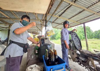 SEORANG penduduk membeli petrol dalam botol di Seberang Perak dekat Pasir Salak, Perak semalam. – UTUSAN/AIN SAFRE BIDIN