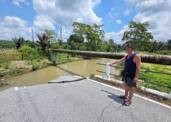 LEE Che Hoo menunjukkan kesan jambatan yang runtuh semasa kejadian kelapa air di Slim River pada Ogos tahun lalu ketika ditemui di Tanjung Malim semalam. – UTUSAN/AIN SAFRE BIDIN