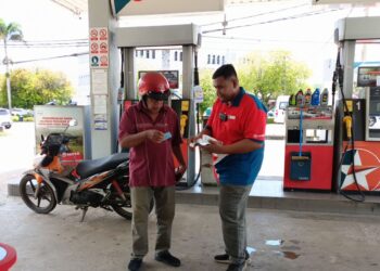 YUSUF Ismail (kiri) dibantu seorang pekerja stesen minyak  mengisi petrol RON95 di bawah program BUDI95 di pekan Baling, Kedah semalam. -UTUSAN/ NORLIA RAMLI