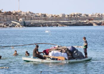 KELUARGA Palestin membawa barangan mereka menaiki bot nelayan ketika melarikan diri ke arah selatan melalui laut dari pelabuhan Gaza City. – AFP