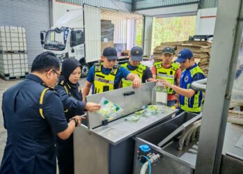 PENGUAT KUASA KPDN dan anggota PDRM ketika menjalankan pemeriksaan selepas serbuan Op Tiris di sebuah kilang di Mantin, Seremban, kelmarin.