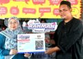 FUZIAH Salleh menyerahkan replika 'Kad Diskaun Khas' Menu Rahmah kepada Wan Ahmad Hafidzul Wan Sulong, 39, di gerainya di Pekan, Pahang. - FOTO/SHAIKH AHMAD RAZIF